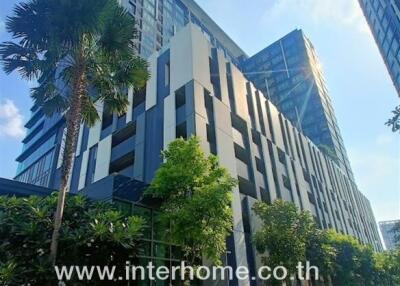 Modern multi-story residential building with greenery and clear blue sky