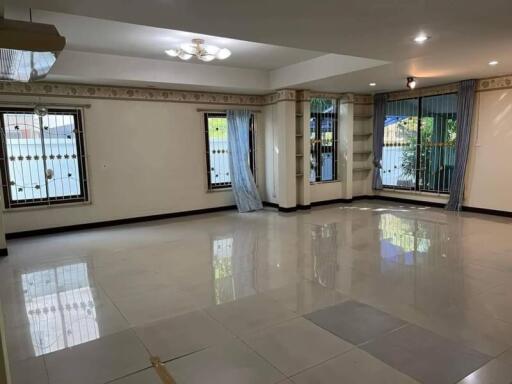 Spacious and well-lit living room with tiled floors and multiple windows