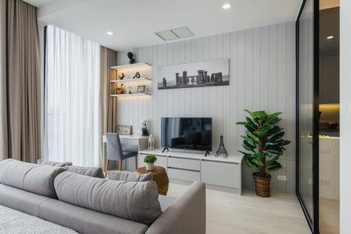 Modern living room with a sofa, TV, desk, and large window