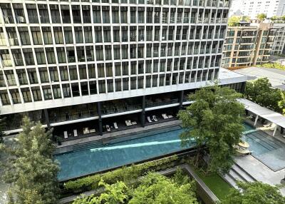 Exterior view of a modern high-rise building with a swimming pool and greenery.