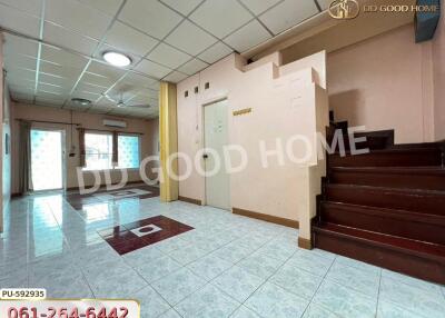 Spacious living area with tiled flooring, staircase, and large windows