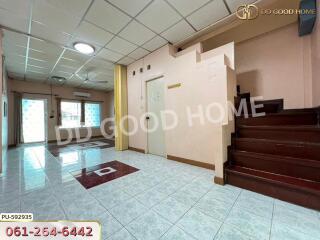 Spacious living area with tiled flooring, staircase, and large windows