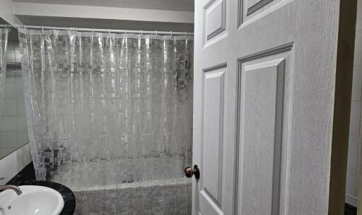 Modern bathroom with sink, mirror, and bathtub with shower curtain