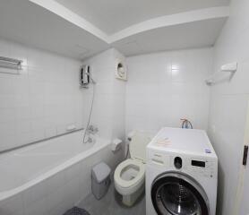 White-tiled bathroom with bathtub and washing machine