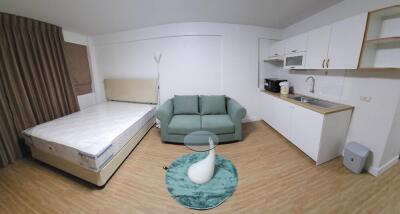 Cozy studio apartment with bed, sofa, and kitchen area