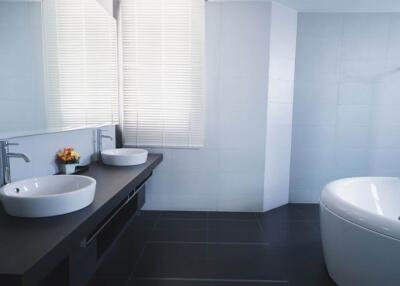 Modern bathroom with dark tiles, large mirror, and dual sinks