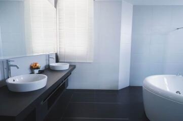 Modern bathroom with dark tiles, large mirror, and dual sinks