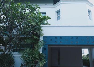 Front view of a modern house with a carport and surrounding greenery