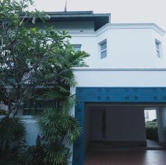 Front view of a modern house with a carport and surrounding greenery