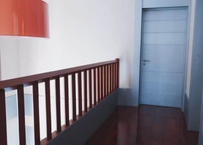 Hallway with wooden flooring and railing, light fixture and door