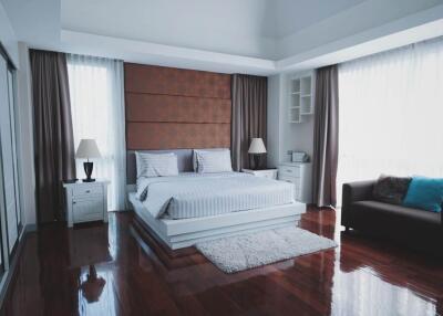 Modern bedroom with large windows, wooden floor, and contemporary furniture