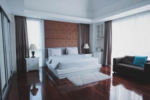 Modern bedroom with large windows, wooden floor, and contemporary furniture