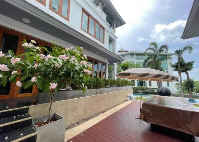 Outdoor patio area of a modern building with covered furniture, a large plant, and an umbrella