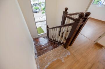 Staircase with wooden handrails and transparent protective wrap on the steps