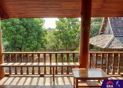 A spacious balcony with wooden furniture overlooking lush greenery.