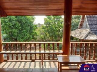 A spacious balcony with wooden furniture overlooking lush greenery.