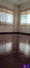 Unfurnished room with wooden flooring and large windows with sheer curtains