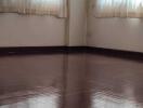 Unfurnished room with wooden flooring and large windows with sheer curtains