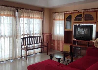 Living room with red sofa, TV, and large windows