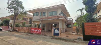 Two-story house with a front yard and a for sale sign