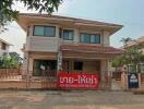 Front view of a two-story house with a sign in Thai language