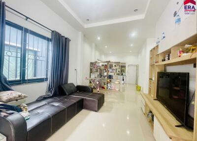 Modern living room with a black sectional sofa, TV unit, and bookshelf