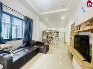 Modern living room with a black sectional sofa, TV unit, and bookshelf