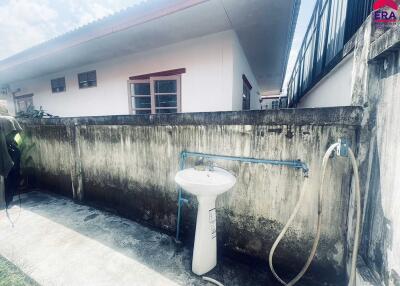 Outdoor utility area with a sink and high wall