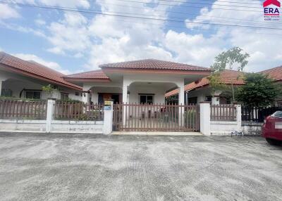 Front view of a residential house with a fenced yard and a car parked outside