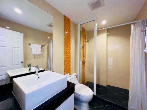 Modern bathroom with a large mirror, sink, toilet, and shower area