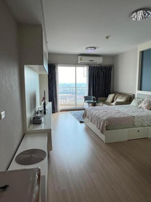 Spacious bedroom with a bed, couch, desk, and a view of the balcony