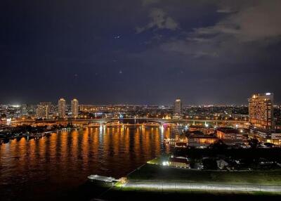 Night view of city skyline with illuminated buildings and river