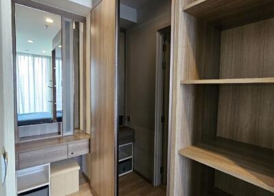 Walk-in closet area with wooden shelves, a vanity mirror, and built-in storage.
