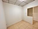 Small empty bedroom with tiled floor and slatted window