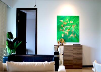 Well-lit living room with modern decor and a green painting on the wall