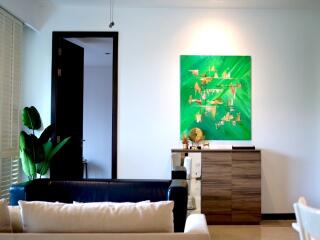 Well-lit living room with modern decor and a green painting on the wall