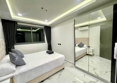 Contemporary bedroom with large mirror, bed, and window with night view.