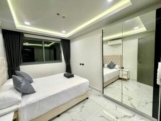 Contemporary bedroom with large mirror, bed, and window with night view.