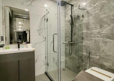 Modern bathroom with glass shower enclosure and marble walls