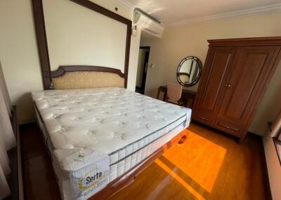 Spacious bedroom with large bed, wooden furniture, and ample sunlight