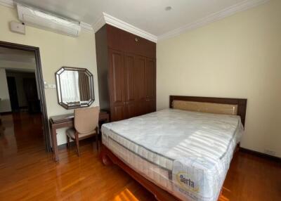 Bedroom with wooden flooring, bed, wardrobe, desk, and air conditioning unit