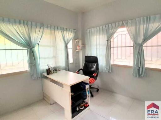 A home office with a desk, chair, and windows with curtains