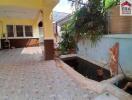 Outdoor area with tiled flooring, small fish pond, and plants