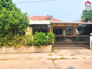 Front view of a residential house with a fenced yard and carport