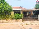 Front view of a residential house with a fenced yard and carport