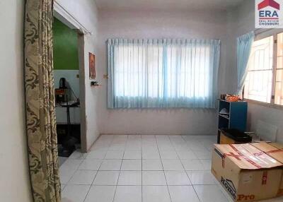 Empty room with tiled floor and windows with blue curtains, adjacent to a workspace