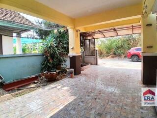 Covered carport or garage area with tiled floor and garden views