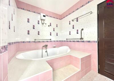 Bathroom with a bathtub, pink and white tiles, and wooden door