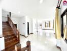 Spacious living area with large windows and wooden staircase