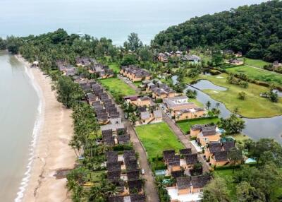 Aerial view of a beachfront village with houses, greenery, and ocean